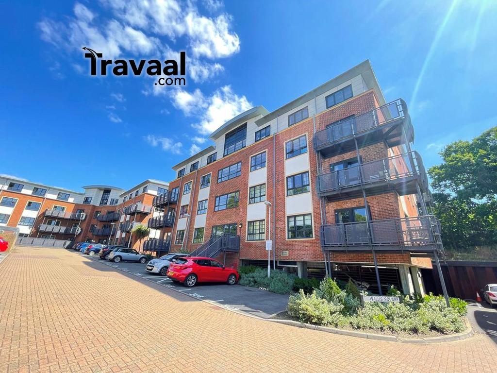 a brick building with cars parked in a parking lot at Travaal.©om - 2 Bed Serviced Apartment Farnborough in Farnborough