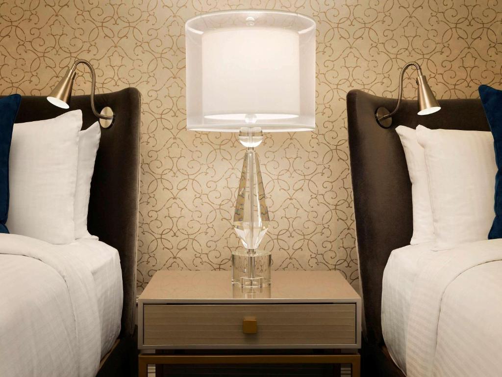 a lamp on a table between two beds at Fairmont Empress Hotel in Victoria