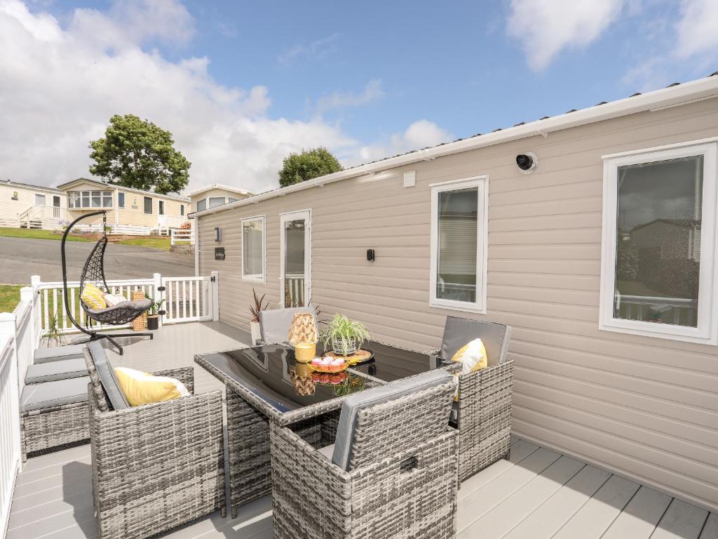 a patio with wicker chairs and a table at Moondunes - Pwllheli in Pwllheli