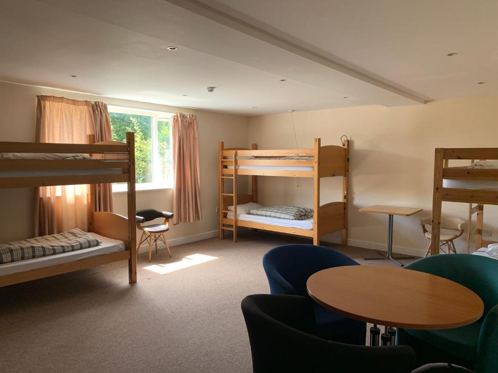 a room with bunk beds and a table and chairs at Stonehenge Hostel - YHA Affliated in Amesbury