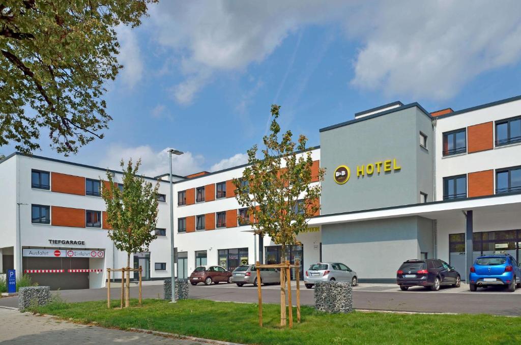 a large white building with cars parked in a parking lot at B&B Hotel München City-Ost in Munich