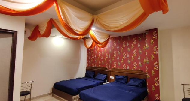 a bedroom with two blue beds and a curtain at Hotel The Best Relax Inn By WB Inn in New Delhi