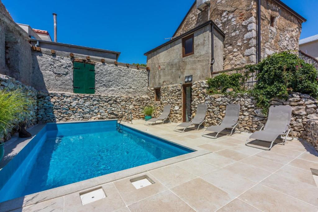 a villa with a swimming pool in front of a stone building at Villa Casa Royal in Bribir