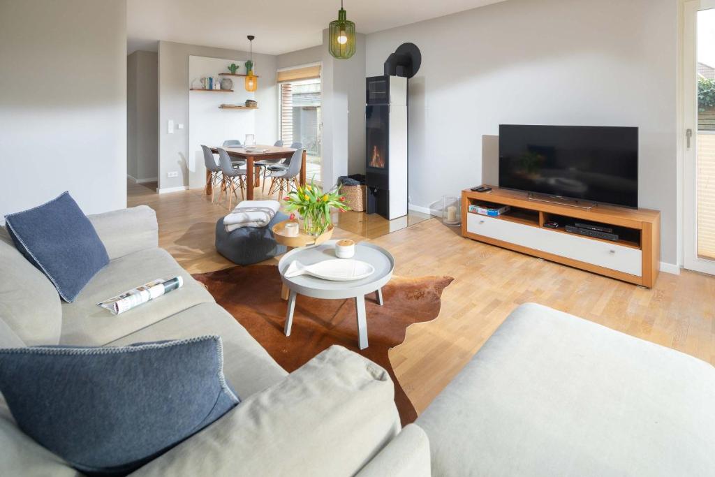 uma sala de estar com um sofá, uma televisão e uma mesa em Mühlenloft em Norderney
