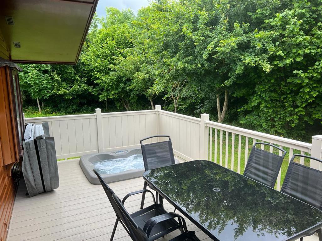 a deck with a table and chairs and a hot tub at Woodland Lodge With Hot Tub in Malton