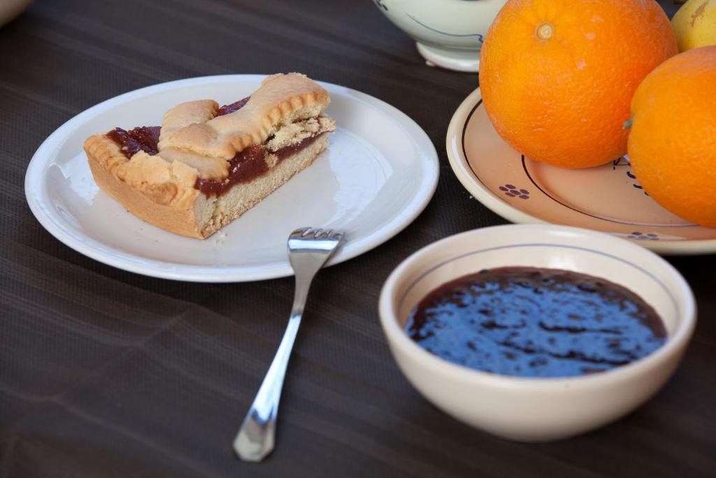 un pezzo di torta su un piatto vicino a un cesto di frutta di Hotel Donatello ad Alberobello