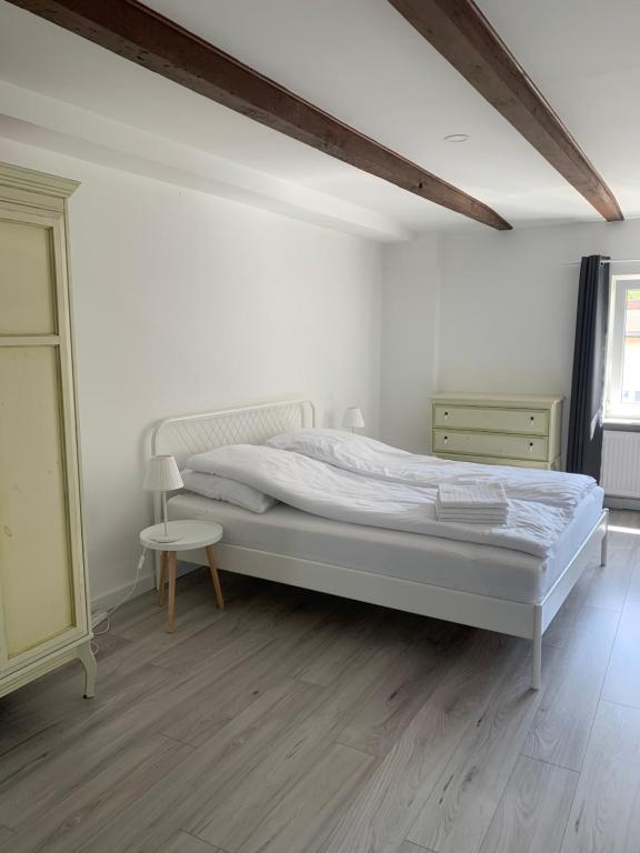 a white bedroom with a bed and a chair at Apartament w Gdyni u podnoża Kamiennej Góry in Gdynia