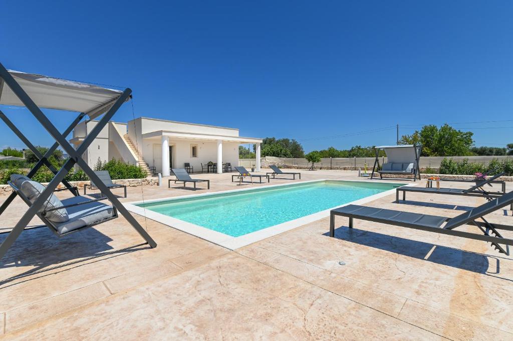 a swimming pool with lounge chairs and a house at Villa Gioena con piscina in San Vito dei Normanni