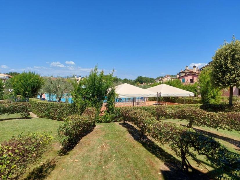 a garden with bushes and trees and tents at Resort il cigno in Peschiera del Garda