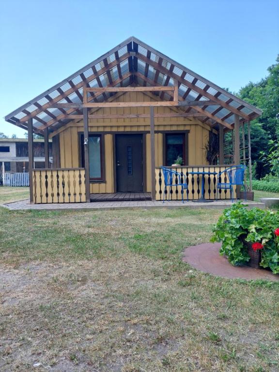 una pequeña casa amarilla con techo de madera en jõekalda kodumajutus en Häädemeeste