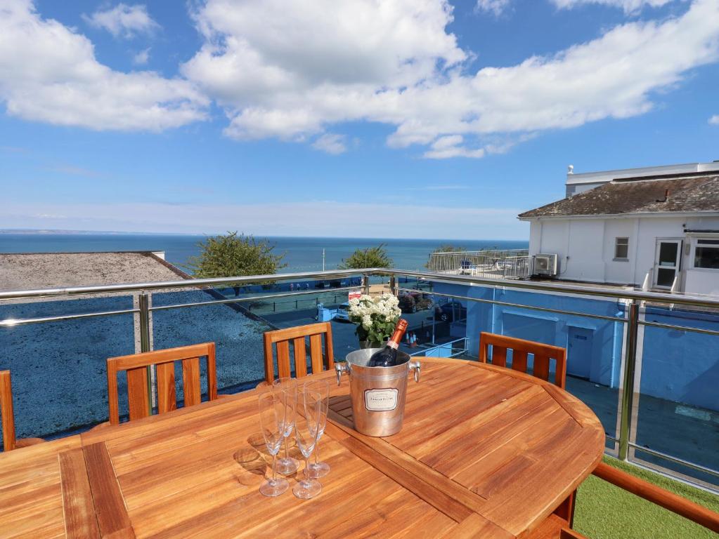 a wooden table on a balcony with a view of the ocean at Apartment at Morningside Hotel in Torquay