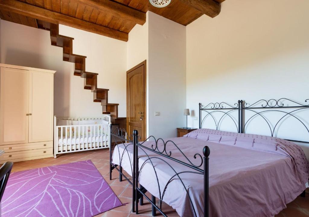 a bedroom with a bed with purple sheets and a staircase at Agriturismo Torre Gialluise in Gesualdo