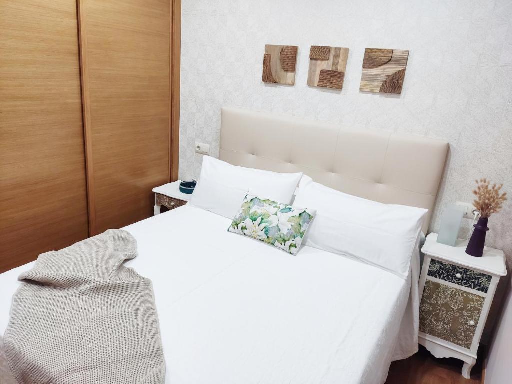 1 dormitorio con cama blanca y almohadas blancas en La Dorada, en Boiro
