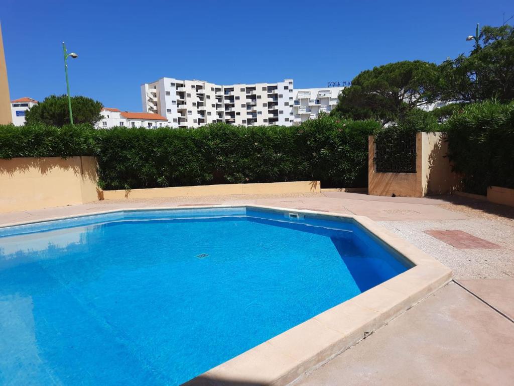 ein großer blauer Pool mit einem hohen Gebäude im Hintergrund in der Unterkunft Appartement en Résidence avec piscine proche mer in Le Barcarès