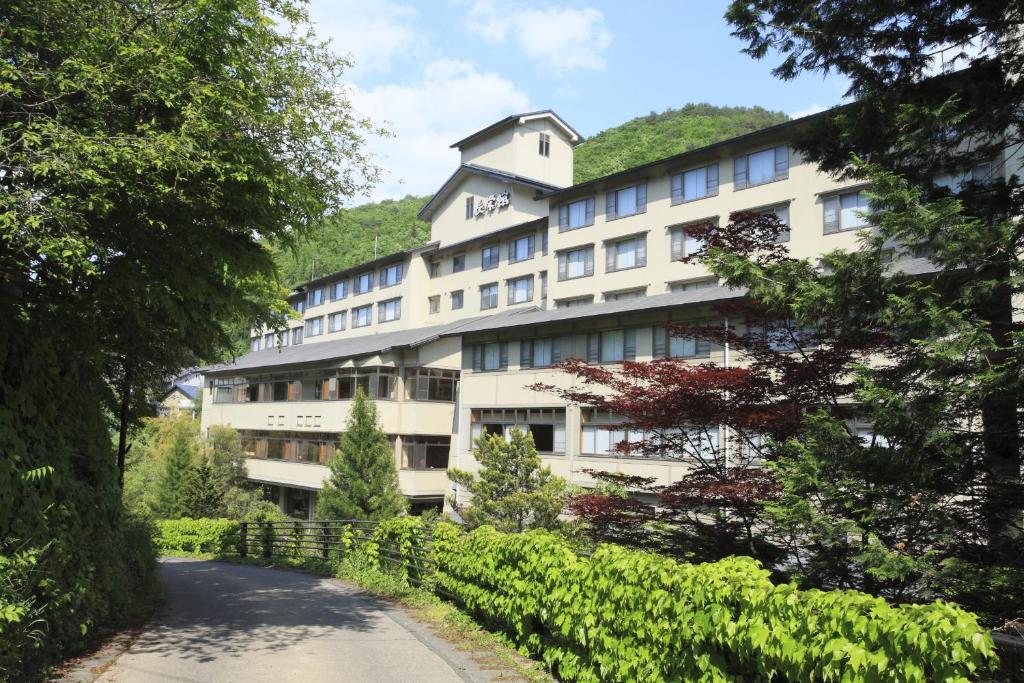 un gran edificio blanco con una colina en el fondo en Oushuku Onsen Choeikan, en Shizukuishi