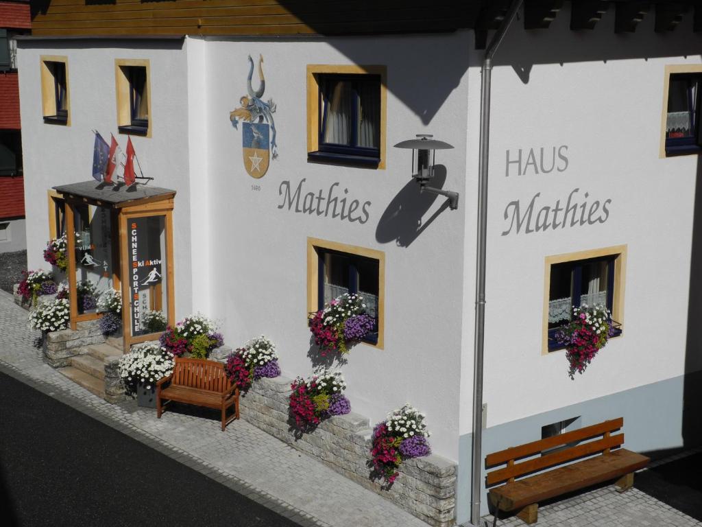 a white building with a bench and flowers on it at Haus Mathies in Stuben am Arlberg