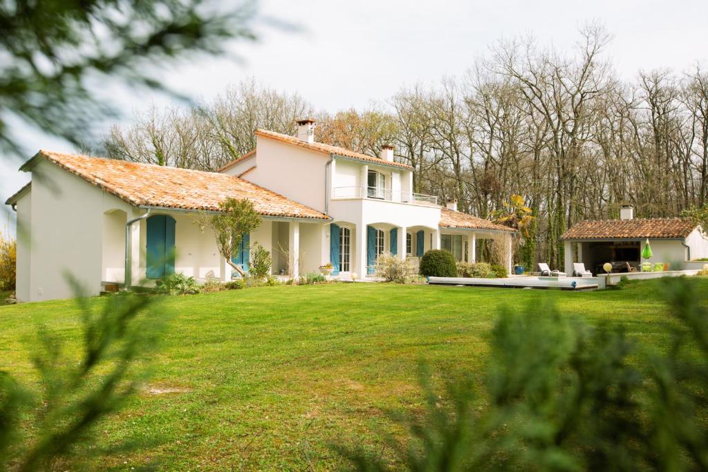 une maison blanche avec une grande cour avec de l'herbe verte dans l'établissement Chambre d'Hôtes La Courbe, à Lugan