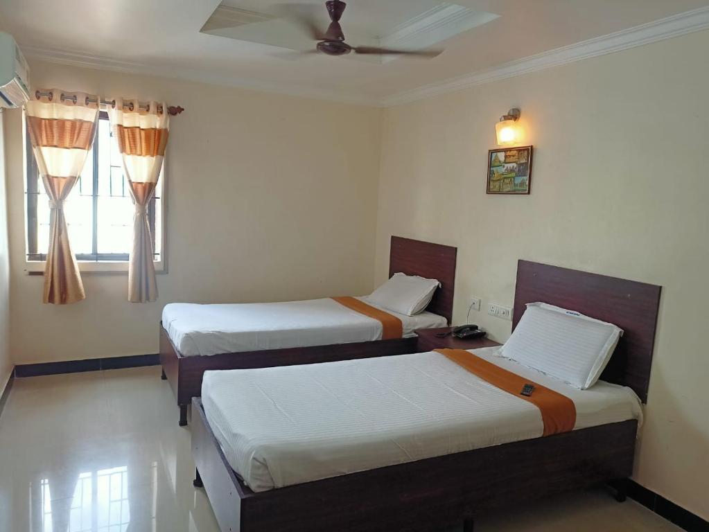 a room with three beds and a ceiling fan at SKY PARK HOTELS in Tiruppūr