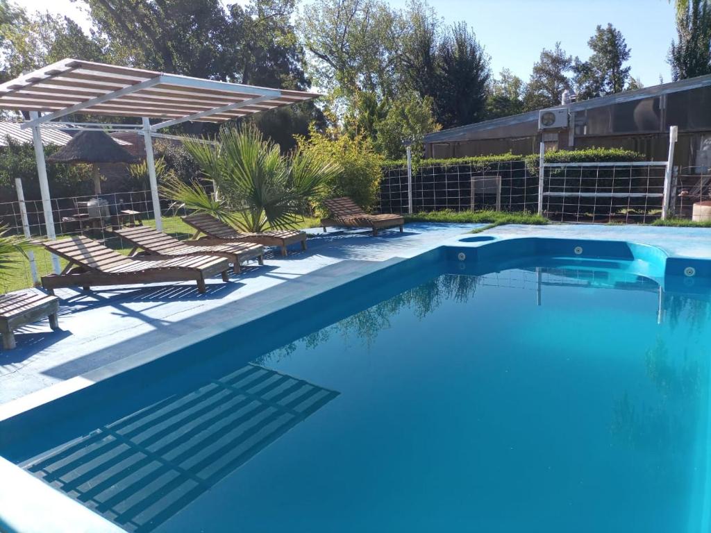 a large swimming pool with chairs and a umbrella at Amanecer en Cuyo in San Rafael