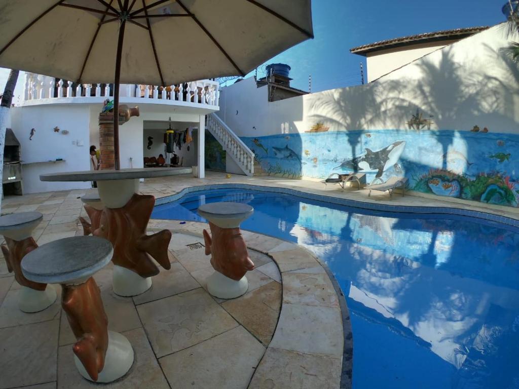 a swimming pool with a table and an umbrella at Canoa Suites & Apartments in Canoa Quebrada