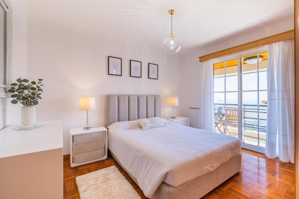 a white bedroom with a bed and a balcony at Casa Flor do Campo in Calheta