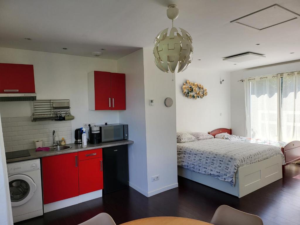 een slaapkamer met een bed en een keuken met rode kasten bij maisonnette à 10min de disney in Jossigny