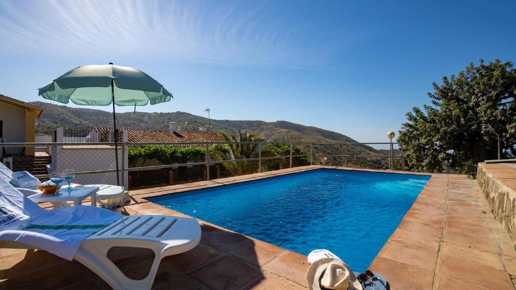 una piscina con 2 sillas y una sombrilla en Casa Campo Chimenea Rincón de la Victoria by Ruralidays, en Rincón de la Victoria