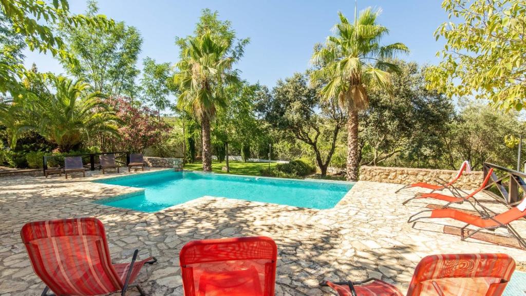 una imagen de una piscina con sillas y árboles en La Jacaranda Hornachuelos by Ruralidays, en Hornachuelos