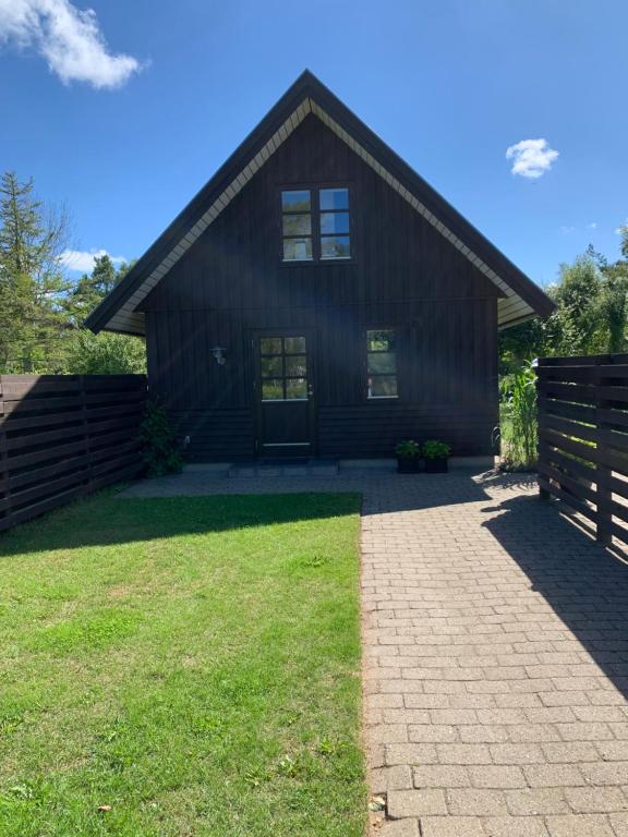 una gran casa de madera con un patio de hierba frente a ella en Hytten, en Ålbæk
