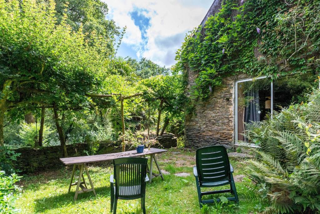una mesa y dos sillas en un jardín en Moments d exception dans cette maison entouree de verdure, en Rochefort-en-Terre