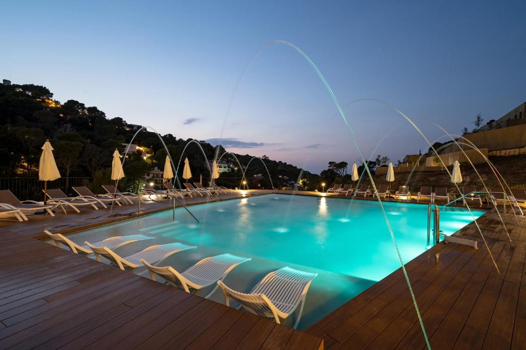 una piscina con tumbonas en una terraza de madera en TALAIA PLAZA ECORESORT BEGUR en Begur