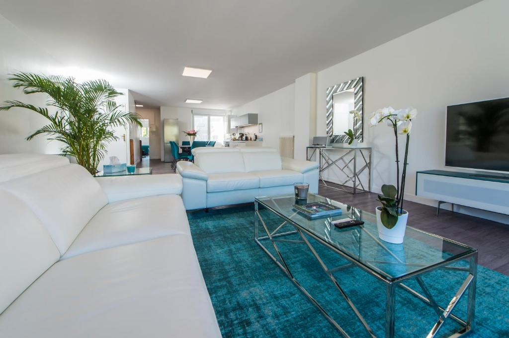 salon z białą kanapą i stołem w obiekcie Suites Mana - Le Manaloft, Chic et moderne avec salle privée de Fitness en plein centre-ville de Rethel w mieście Rethel