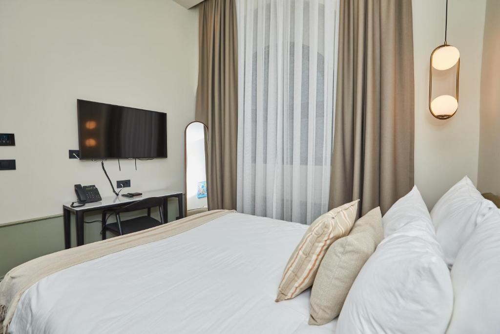 a bedroom with a bed with white sheets and pillows at Martis Forum Heritage Hotel & Residence in Poreč