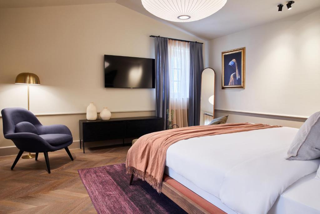 a bedroom with a bed and a chair and a television at Martis Forum Heritage Hotel & Residence in Poreč