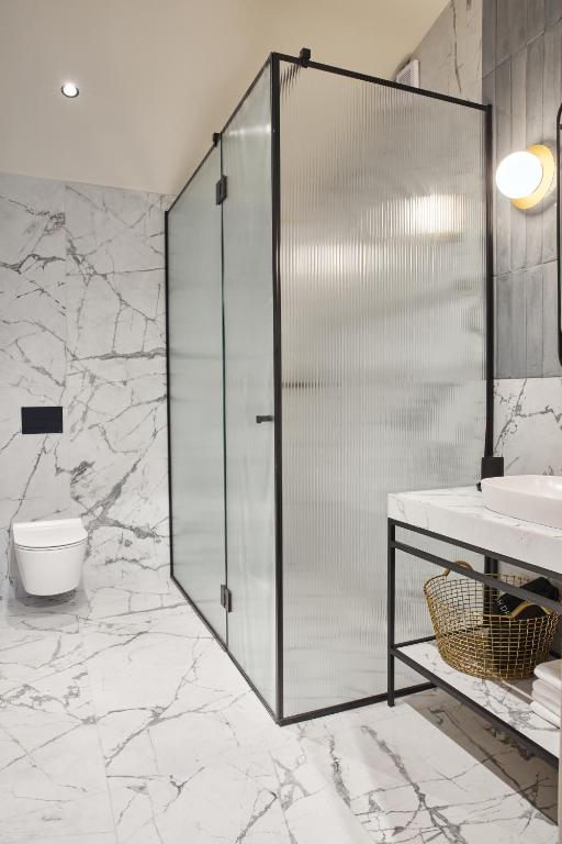 a bathroom with a shower and a toilet and a sink at Martis Forum Heritage Hotel & Residence in Poreč