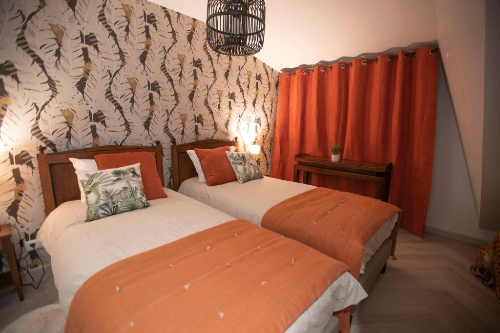 two beds in a room with orange curtains at Chambre Jungle dans maison d'hote "Le Petit Clouet"- Rochecorbon in Rochecorbon