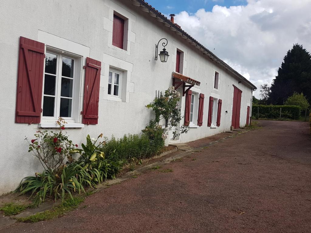 Country Homes Gite 2 في Saulgé: مبنى أبيض بنوافذ مغمضة حمراء وممر