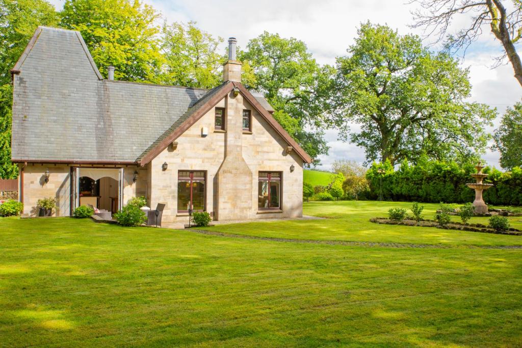 an old stone house with a grass yard at Stunning 4 bedroom country house - Hot Tub & Sauna in Glasgow