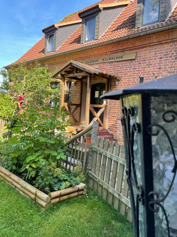 ein Haus mit einem Holzzaun davor in der Unterkunft Gästehaus Kleiner Wacholder in Bad Doberan