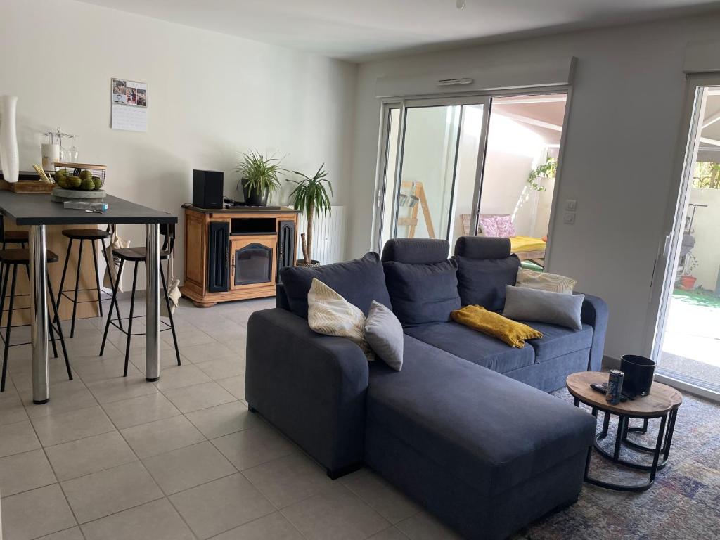 - un salon avec un canapé bleu et une table dans l'établissement Appartement avec terrasse proche de Rennes, à Saint-Jacques-de-la-Lande