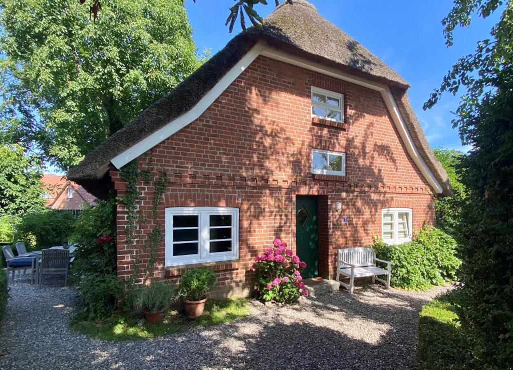 1100 - Designer-Reetdach-Kate في Riepsdorf: منزل من الطوب صغير مع سقف من القش