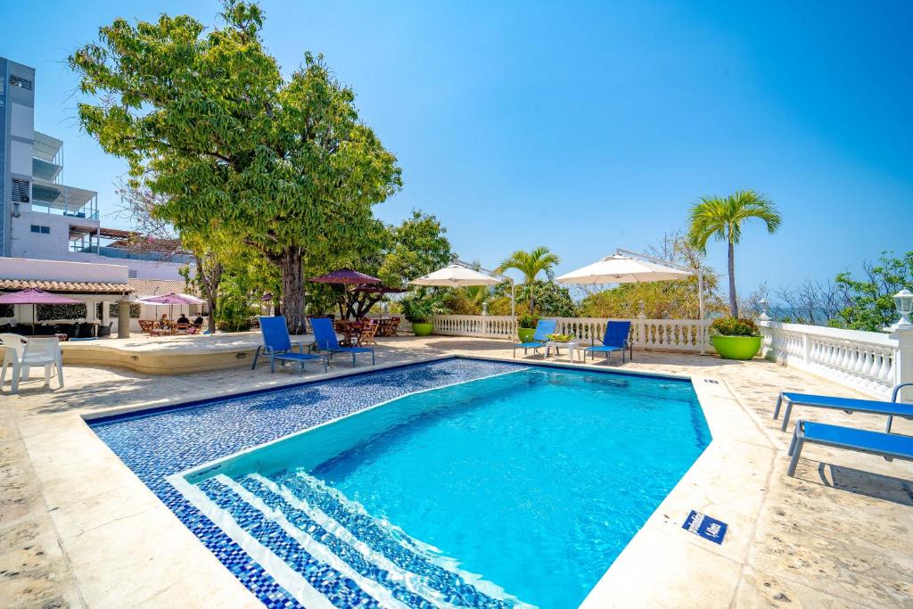 a swimming pool with blue chairs and umbrellas at Santorini Villas del Mar Santa Marta in Santa Marta