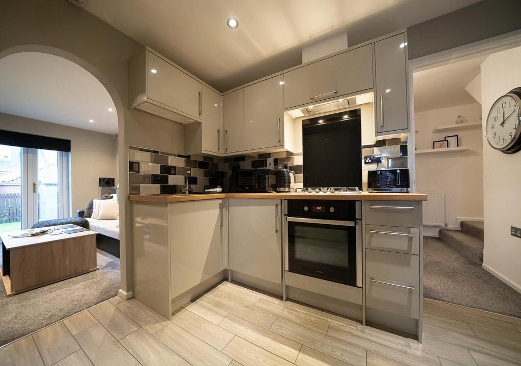 eine Küche mit Küchengeräten aus Edelstahl und ein Wohnzimmer in der Unterkunft The Hideaway Sherburn in Elmet in Sherburn in Elmet