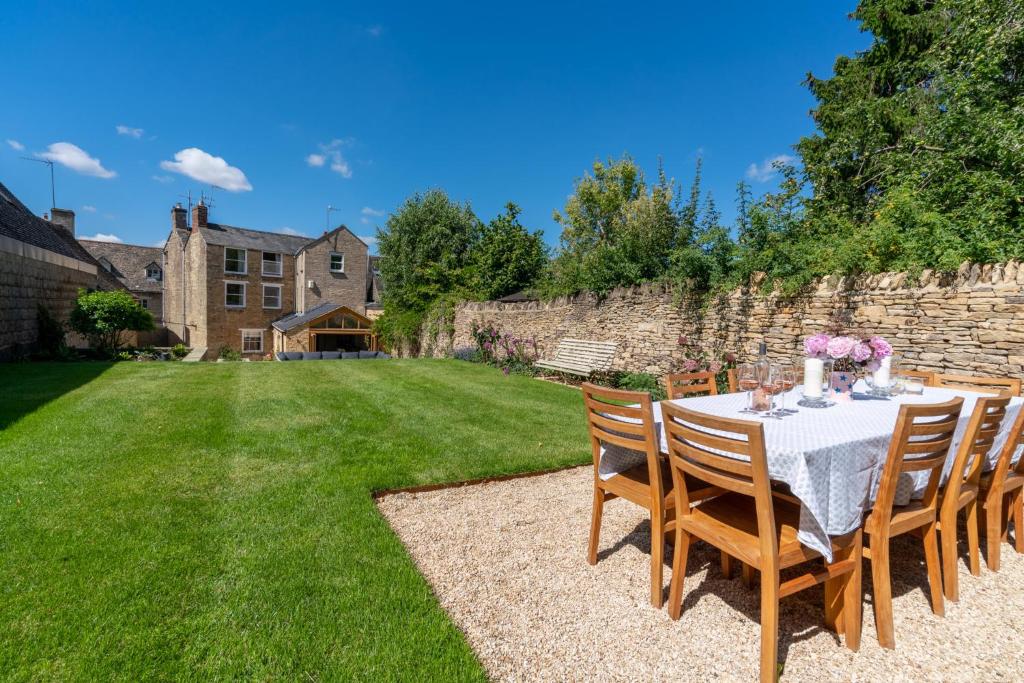 a table and chairs in a yard with a stone wall at Merchant House in Charlbury