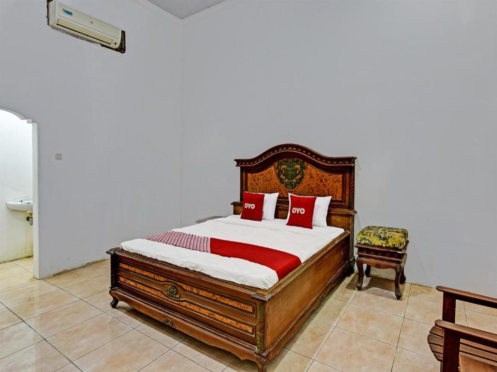 ein Schlafzimmer mit einem Holzbett und einem Stuhl in der Unterkunft OYO 3479 Hotel Intan in Banyumas