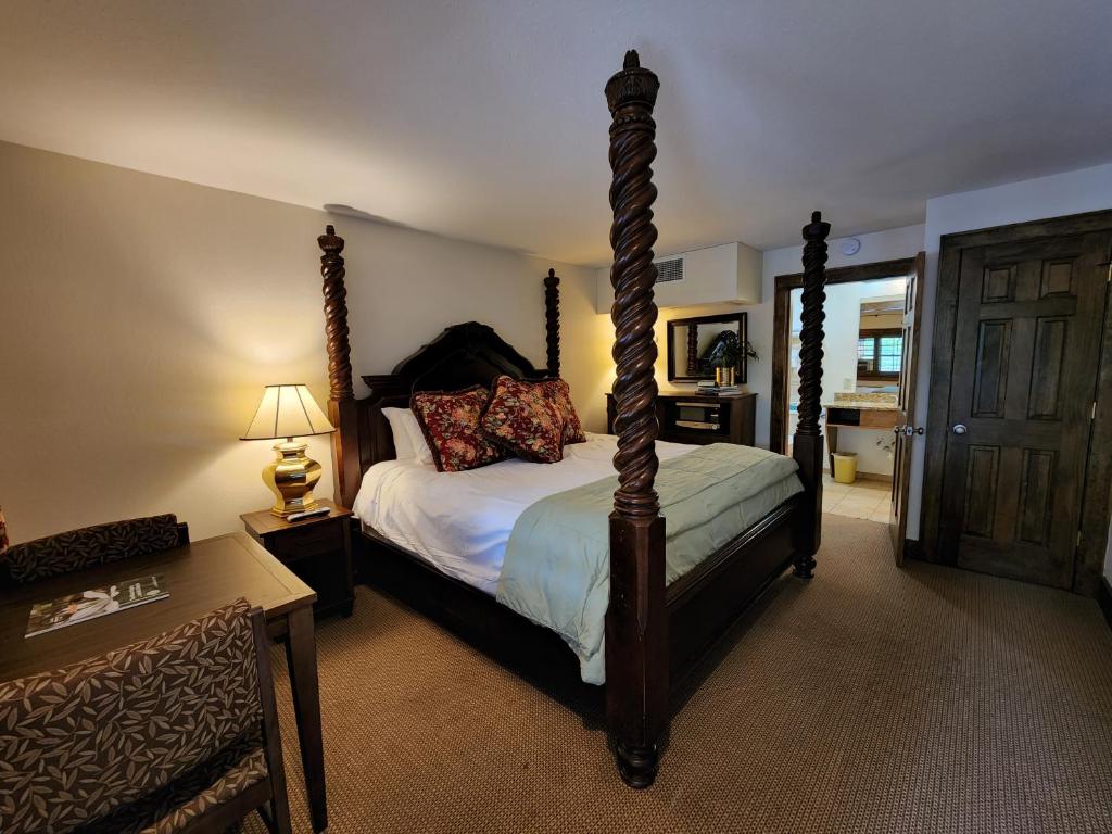 a bedroom with a four poster bed and a table at The Inn at Shady Lawn in Newland