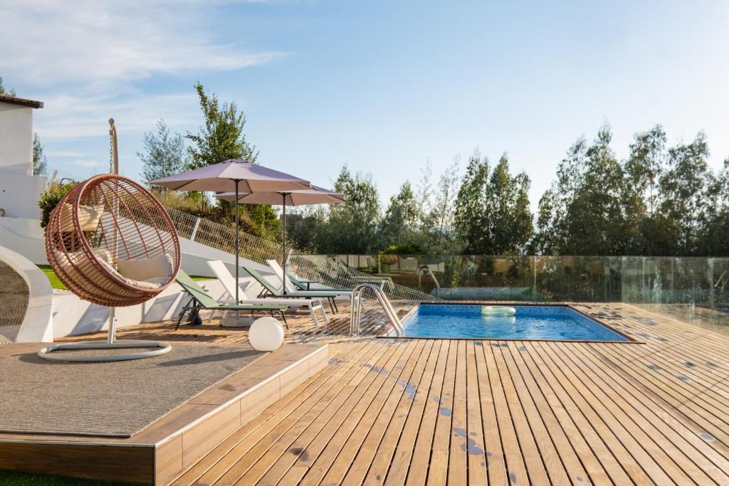 um deque de madeira com uma piscina e um guarda-sol em Casa da Bina em Paredes