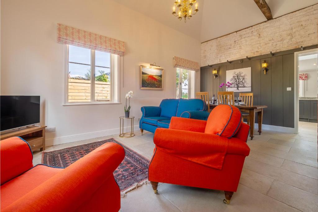 a living room with red chairs and a tv at Luxurious rural retreat - Holt Coach House in Sudbury