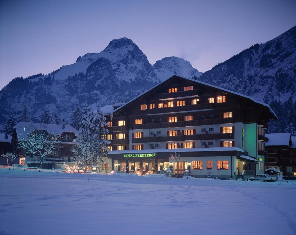 un gran edificio en la nieve frente a una montaña en Bernerhof Swiss Quality Hotel en Kandersteg