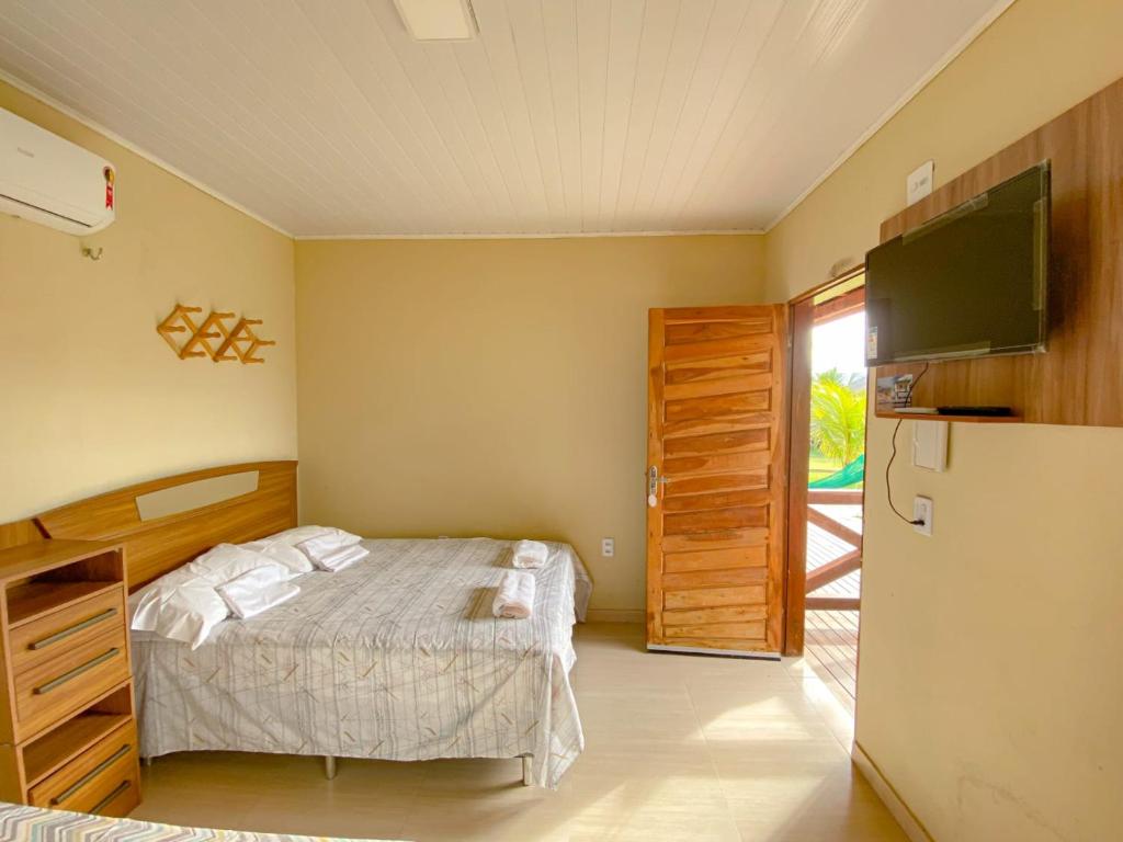 a bedroom with a bed and a tv and a refrigerator at Pousada Brisa do Mar in Barrinha